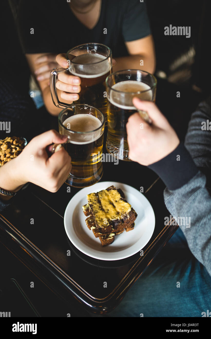 Les gens, les loisirs et les boissons concept - close up of male hands tintement des verres à bière et des bretzels au bar ou au pub Banque D'Images