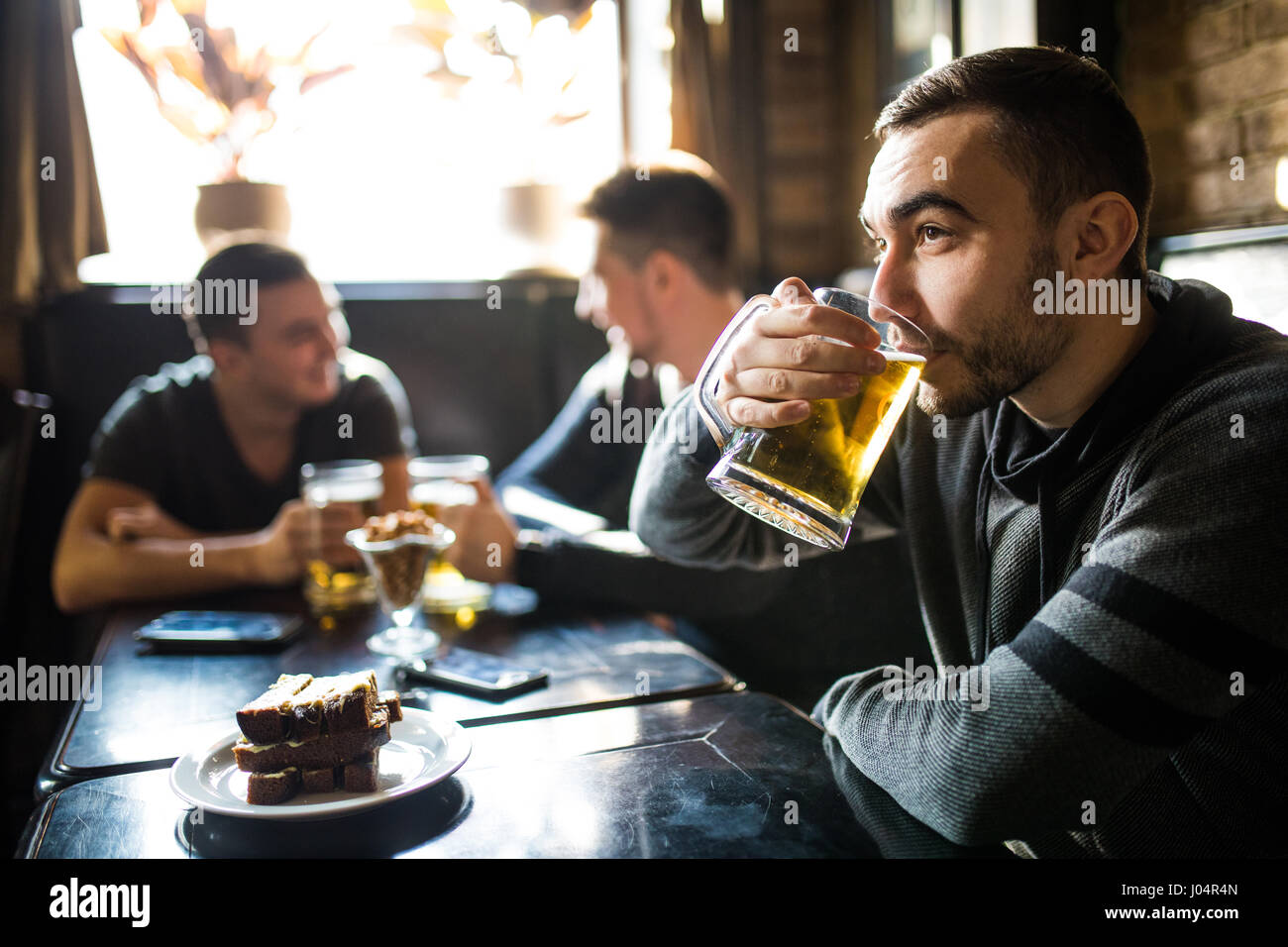 L'homme de boire de la bière devant à discuter entre amis boire dans un pub. Banque D'Images