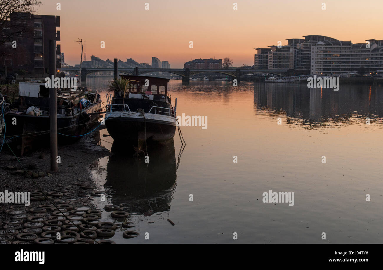 House Boats sont échoué sur le côté de la Tamise au coucher du soleil à Battersea Riverside dans l'ouest de Londres, avec le pont de chemin de fer et vacances buiildi Banque D'Images