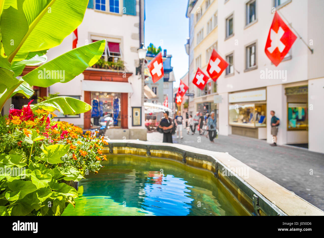 Centre historique de la ville de Zurich avec Swiss drapeaux suspendus bâtiments avec effet de flou sur l'arrière-plan flou d'une journée ensoleillée en été, Suisse Banque D'Images