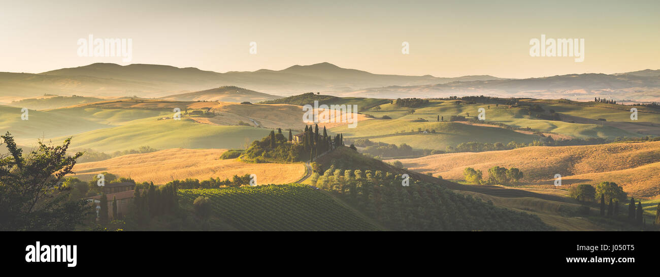 La vue classique du paysage pittoresque de la Toscane avec célèbre ferme au milieu de collines et de vallées idylliques dans la belle lumière du matin au lever du soleil d'or Banque D'Images