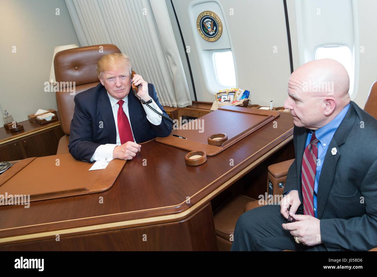 Président américain Donald Trump parle par téléphone avec parle avec les commandants des destroyers lance-missiles USS Porter et USS Ross à bord d'Air Force One en tant que conseiller pour la sécurité nationale, H.R. McMaster regardez le 9 avril 2017 en vol pour Washington, DC. Le président a remercié les commandants et leur personnel pour l'exécution réussie de la grève contre le Shayrat Base aérienne en Syrie. Banque D'Images