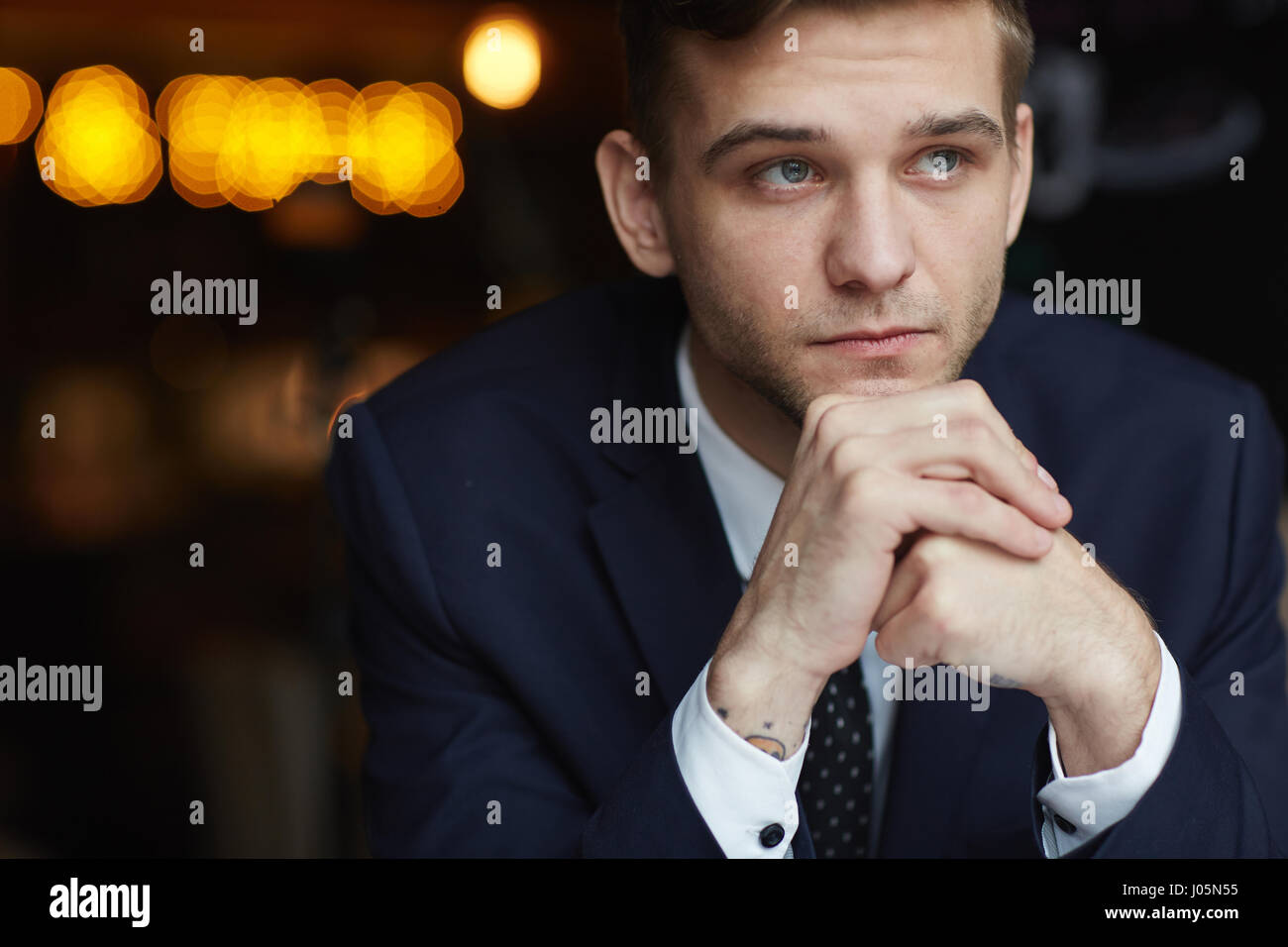 Portrait of young businessman thinking à la suite d'une expression neutre resting head on mains jointes Banque D'Images