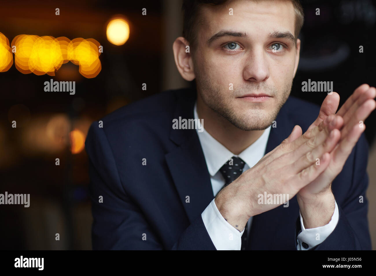 Portrait of young pensive businessman looking away avec de graves expression neutre et se frotter les mains nerveusement, et Banque D'Images