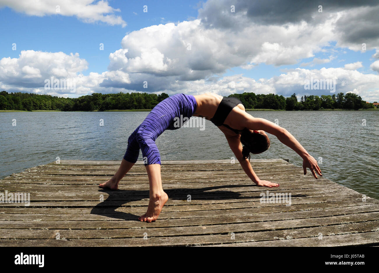 Jeune femme active faisant du yoga positions sur la jetée en bois au bord de lac dans countsydie région polonaise en Mazurie Banque D'Images