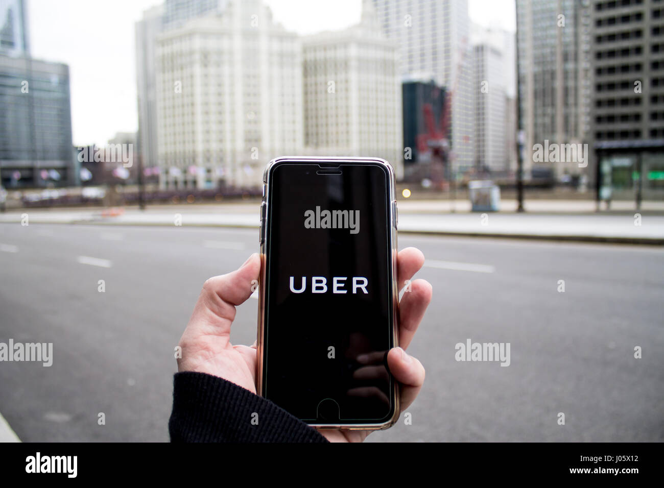 Chicago,IL,USA,Feb-21,2017,Homme tenant un smartphone avec une application Uber dans la ville (pour un usage éditorial uniquement) Banque D'Images