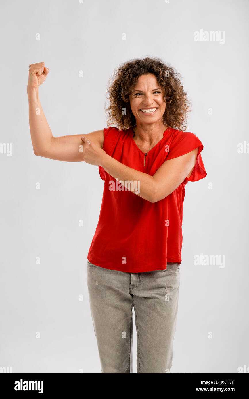 Portrait of a smiling brunette d'âge moyen en piquant dans son muscle du bras Banque D'Images