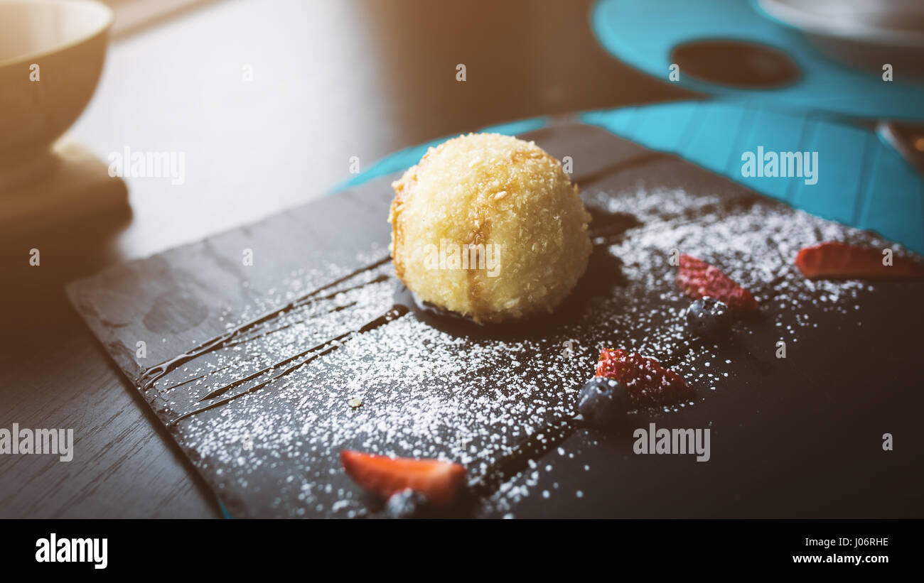 Grillades de la glace dans la noix de coco avec sauce sur la plaque en pierre noire. Arrière-plan de l'alimentation asiatique. Concept de l'alimentation. Restaurant place avec table en bois. Flare Copier sp Banque D'Images