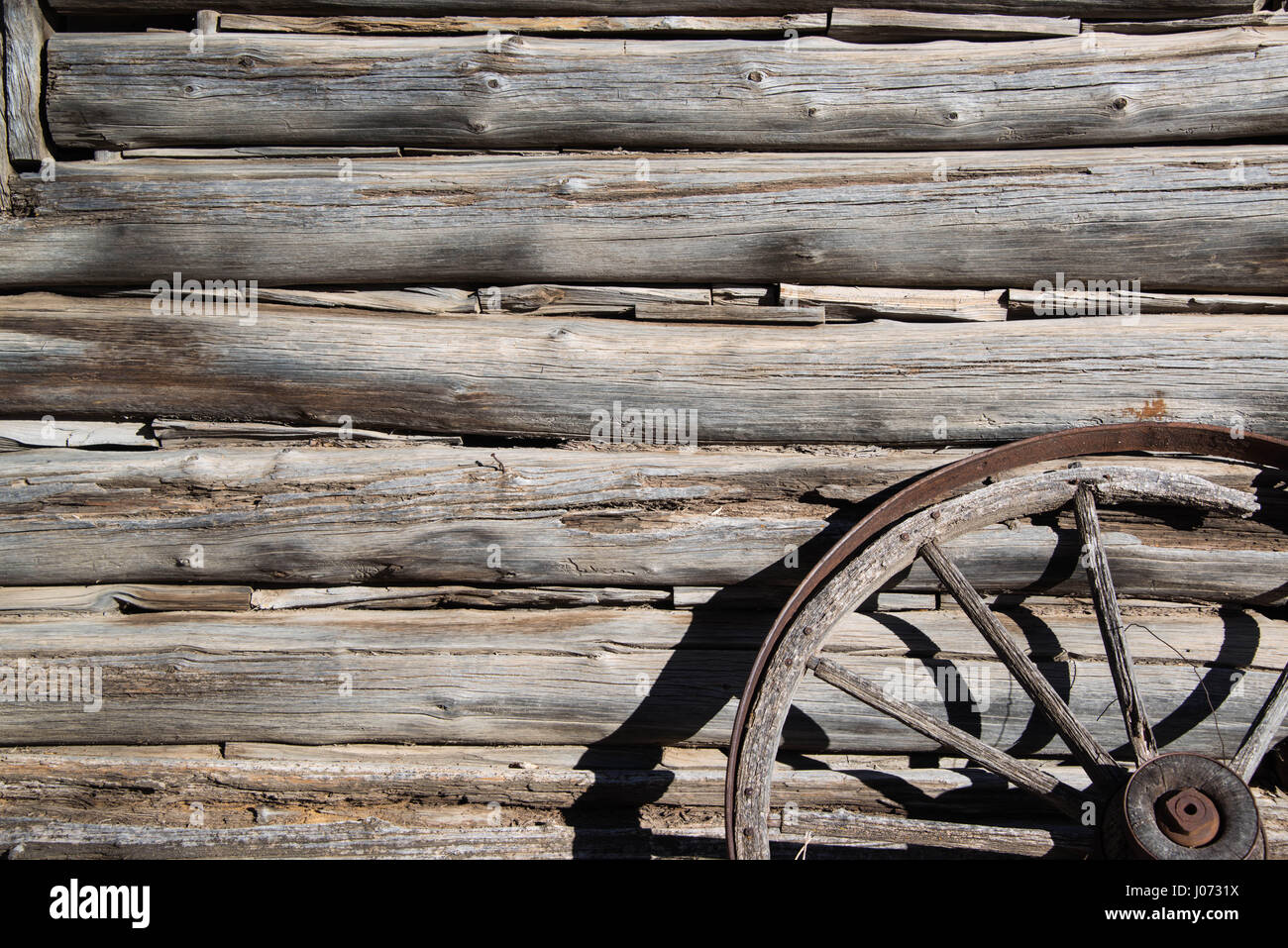 Coupe de main anciens journaux et le fendillement du vieux western cabin et roue de chariot terranova Banque D'Images