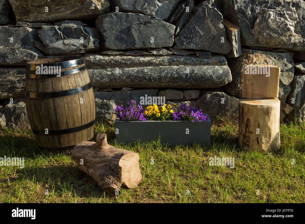 Tabouret en bois fabriqués à la main, tonneau de chêne pot de fleurs violettes et Bell avec un mur de pierres naturelles comme arrière-plan Banque D'Images