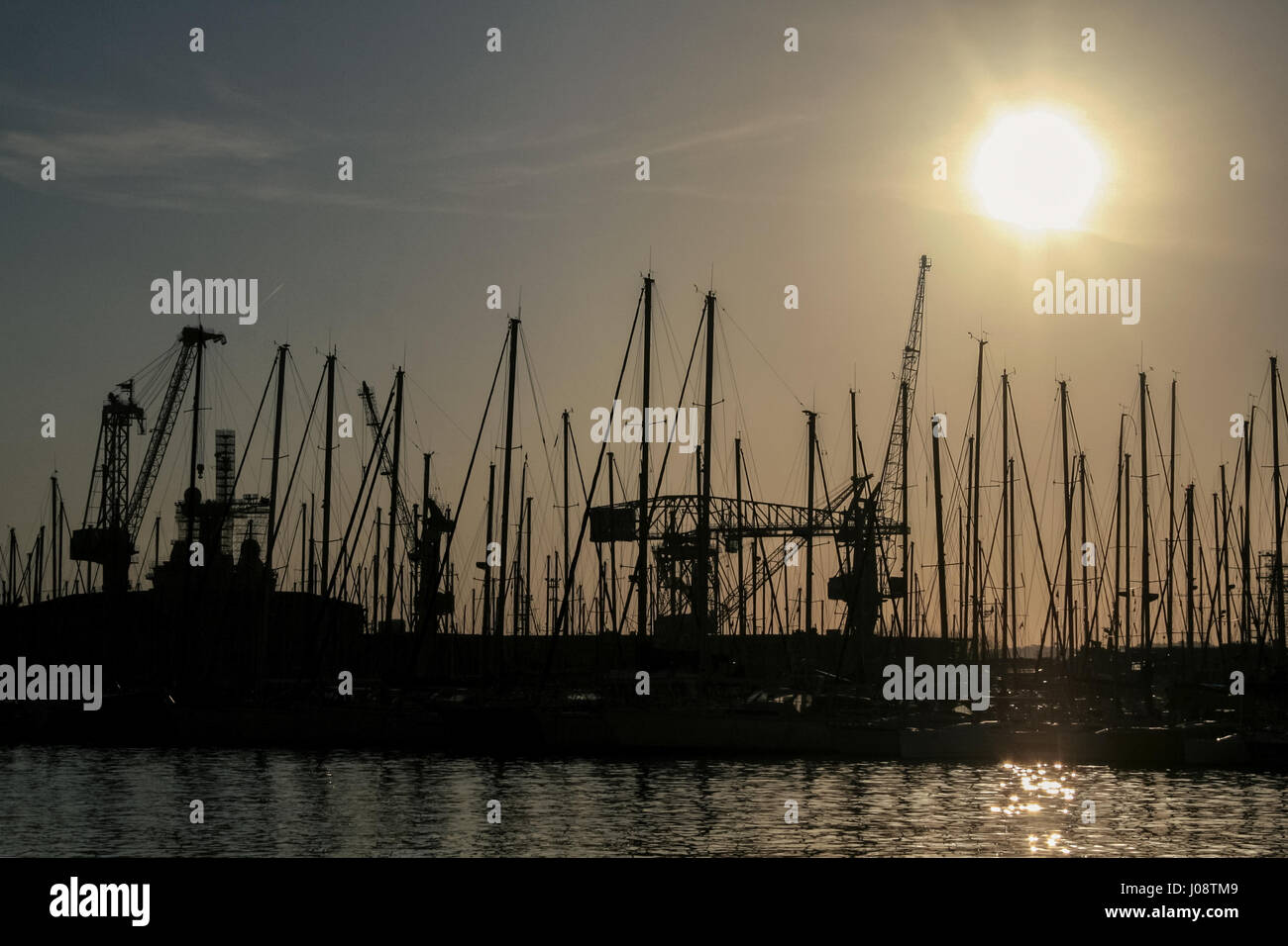 Forme de mâts de bateaux et grues au coucher du soleil dans le port de Toulon, France Photo de bateaux, navires et les grues dans la lumière à la tombée de la nuit dans le port de Toulon, en France. Banque D'Images