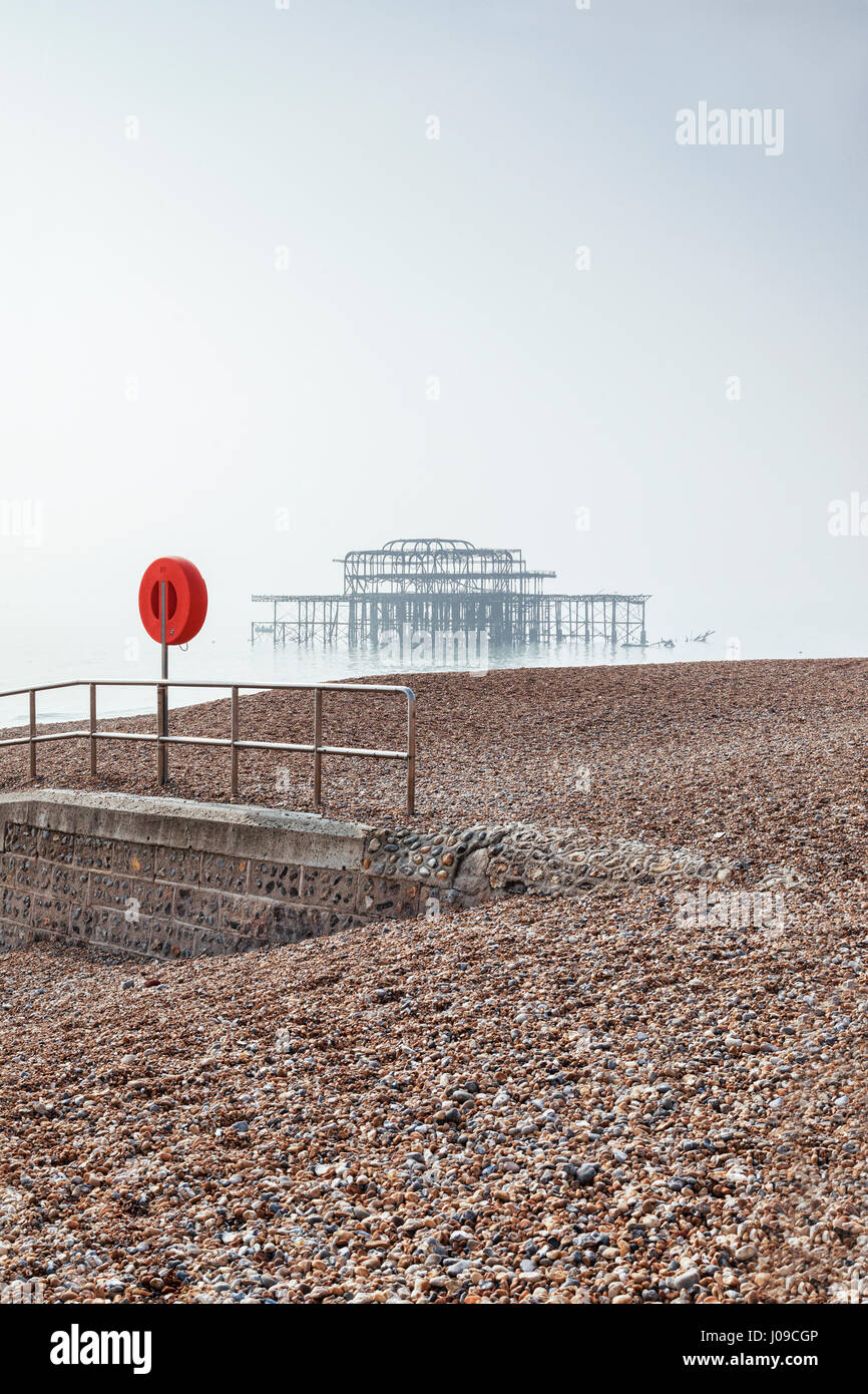 La plage de Brighton et le reste de l'ancienne jetée ouest en un jour brumeux dans télévision lumière, Sussex, England, UK. Banque D'Images