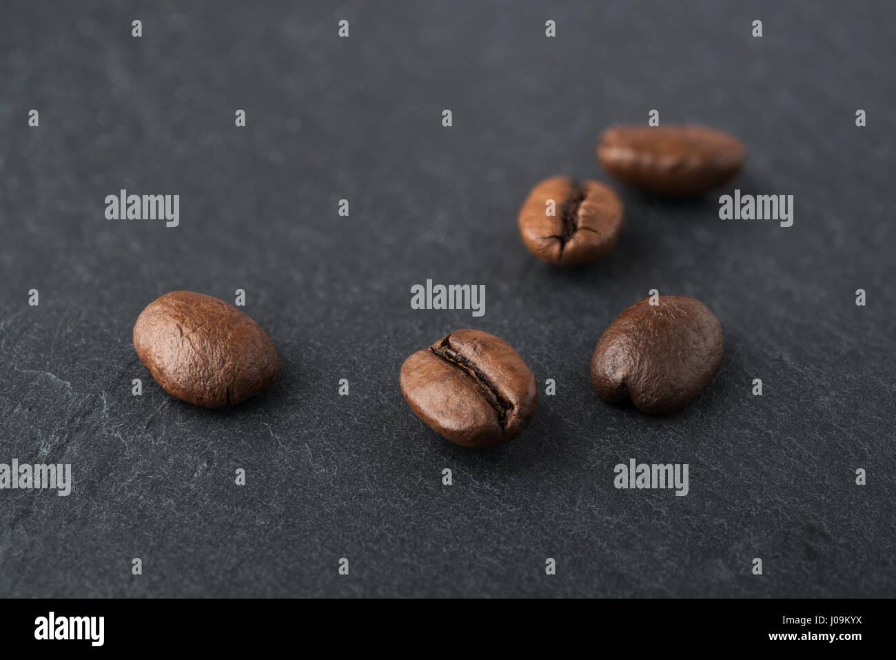 Certains grains de café torréfiés macro shot sur une plaque d'ardoise noire Banque D'Images
