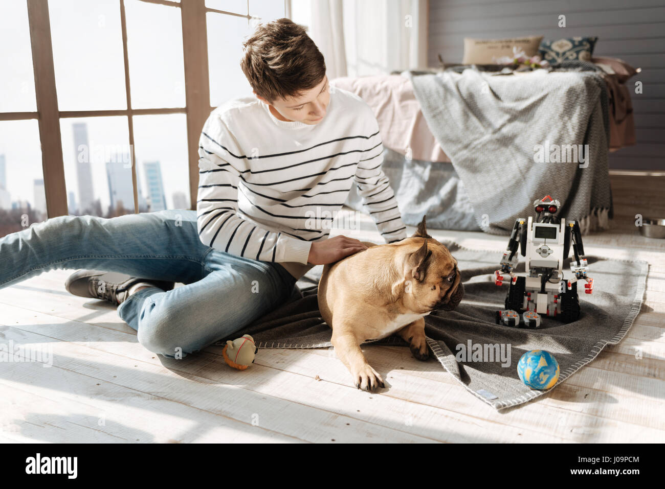 Ne pas le toucher. Garçon attentionné assis sur le tapis en s'inclinant la tête à son animal de compagnie tout en tapotant il Banque D'Images