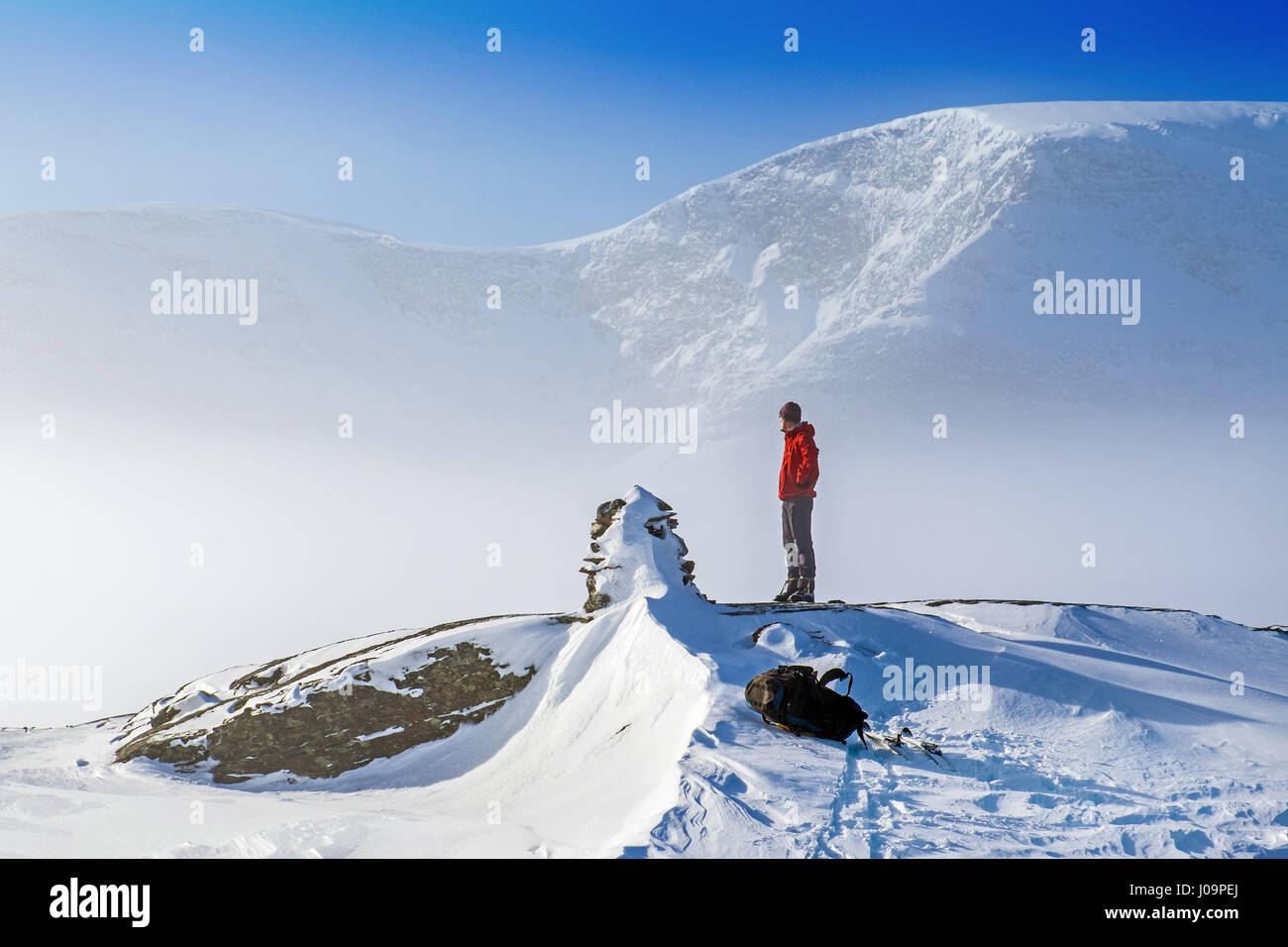 Homme debout sur un sommet enneigé avec brouillard et les montagnes au-delà. Le nord de la Norvège Banque D'Images