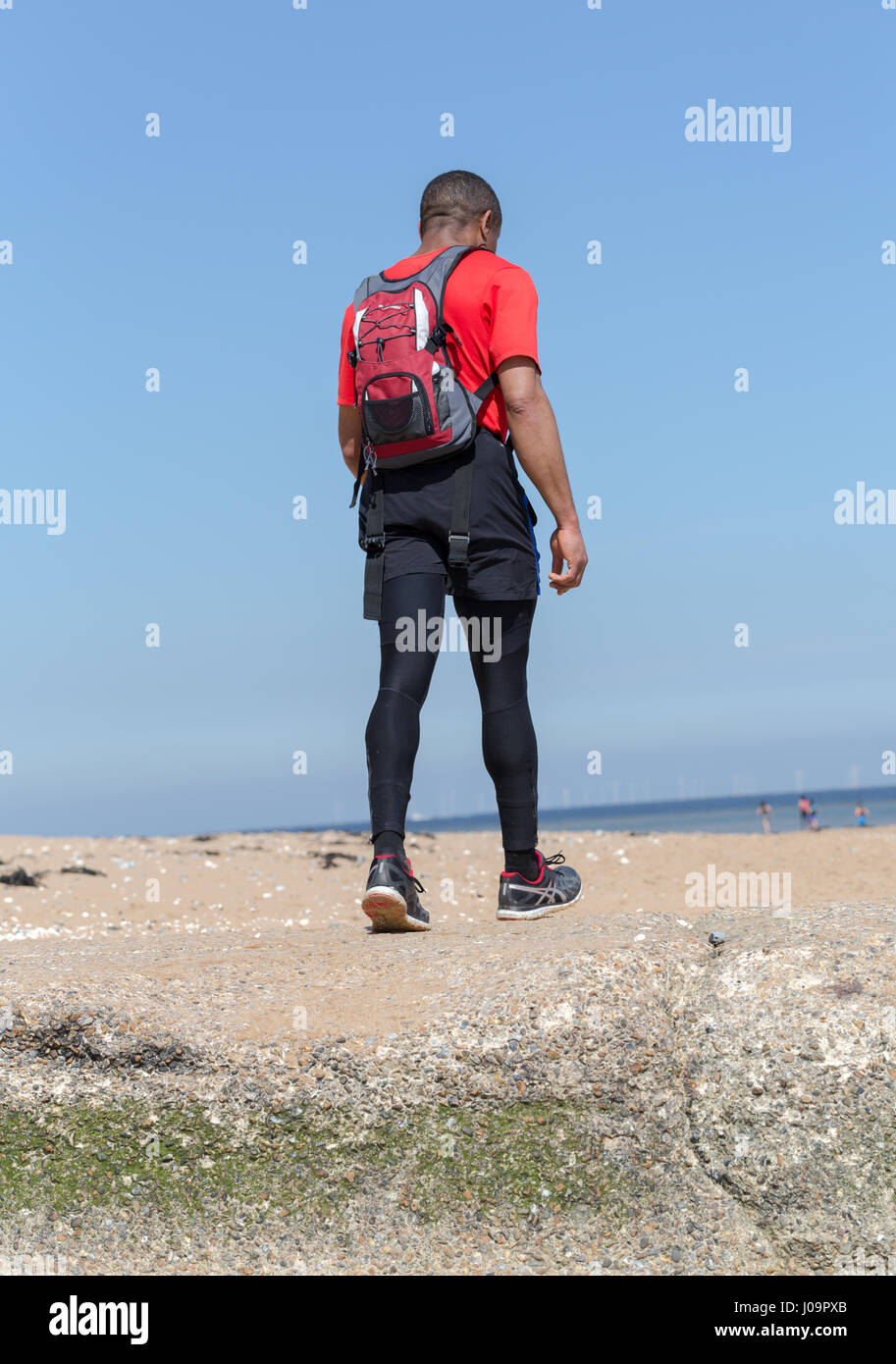 Young adult man fonctionne sur la plage de Margate, Kent, Angleterre Banque D'Images