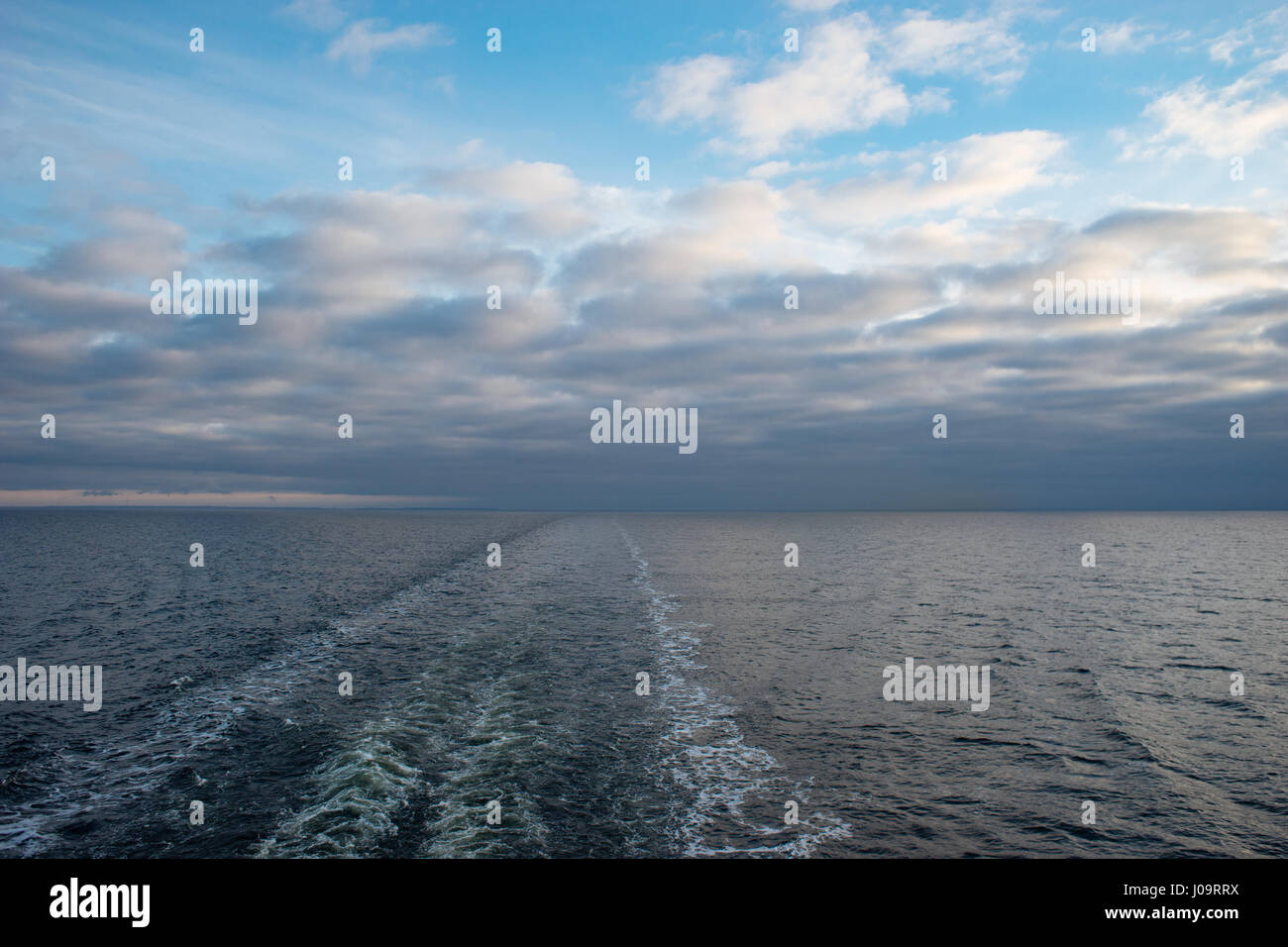 Bateau de croisière service ou trail sur la surface de la mer, trace disparaissant dans l'horizon. Ciel Nuages couvrant Banque D'Images