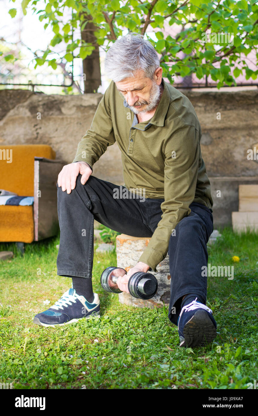 Senior man working out avec haltère en plein air Banque D'Images