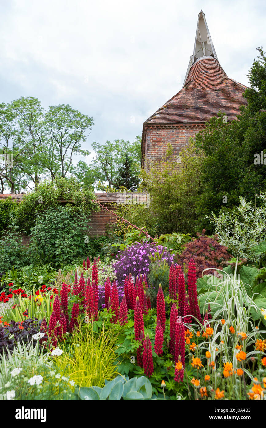 La plantation dans le mur jardin à Great Dixter, Rye, East Sussex, Angleterre, Royaume-Uni, avec l'au-delà Oast House Banque D'Images