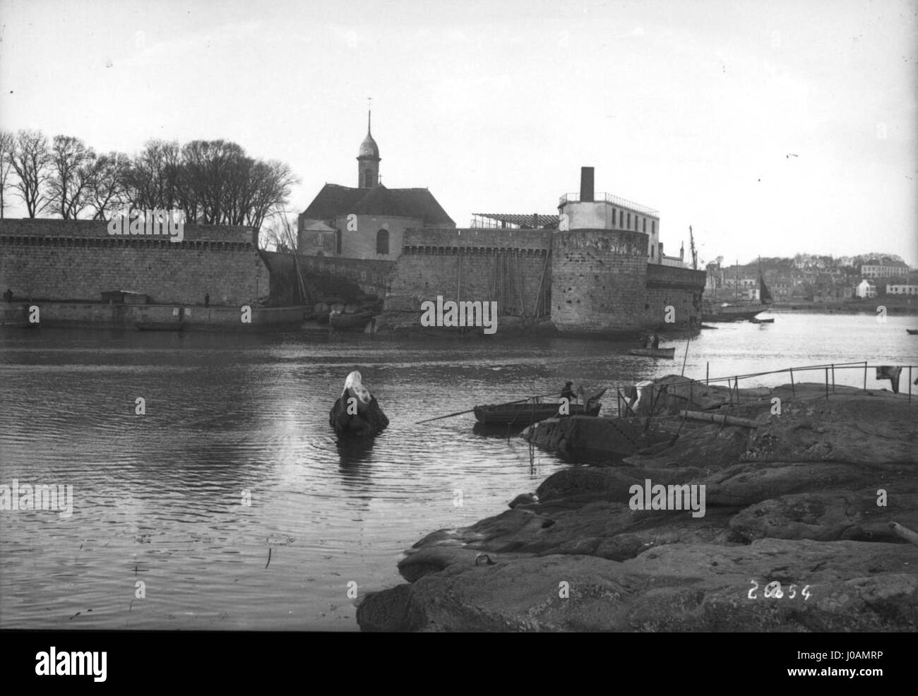 'La ville Close et l'Église Saint-Guénolé' représente la ville fortifiée et l'église Saint-Guénolé dans la ville de Concarneau, en France. La scène met l'accent sur l'architecture médiévale et le cadre côtier, soulignant les fortes fortifications et l'importance historique de ce monument breton. Banque D'Images