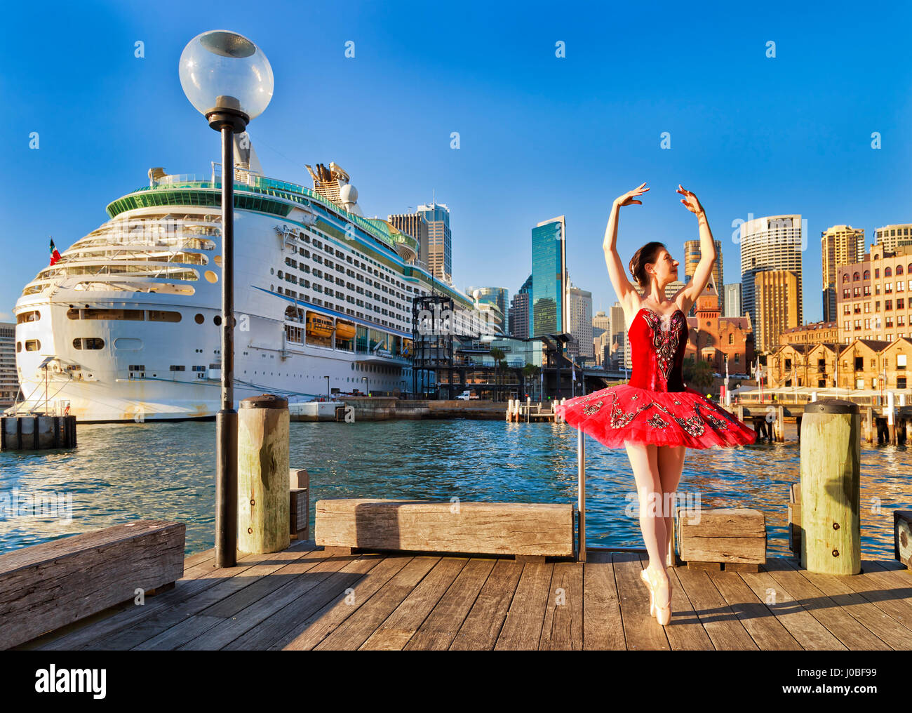 La danse de rue en ballerine chaussures point rouge et les concerts tutu sur un trottoir de bois dans les rochers au bord de l'historique de Sydney contre un quai circulaire Banque D'Images