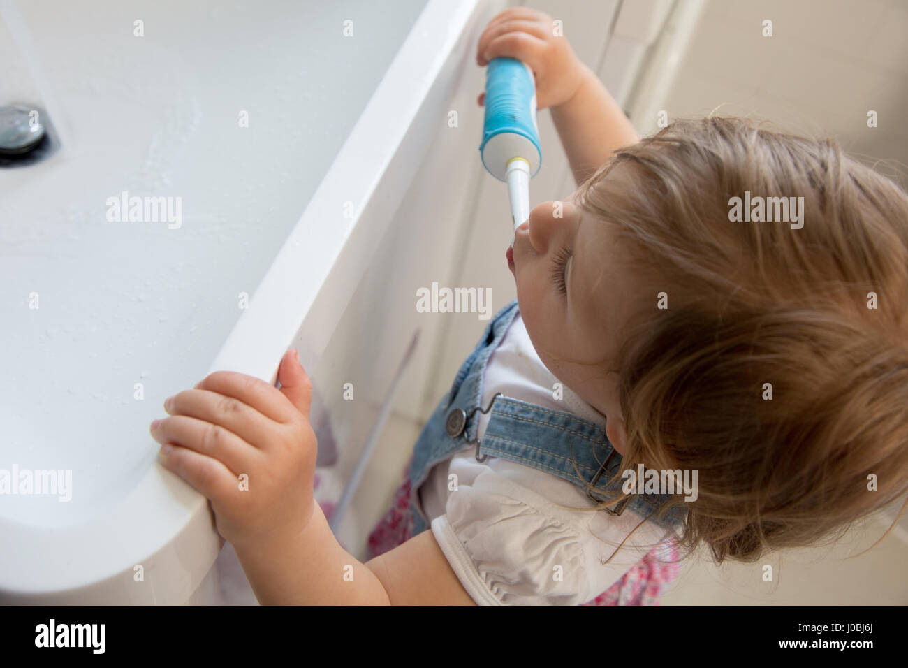 Tout-petit fille se brosser les dents à l'aide d'un adulte brosse à dents électrique. Elle est de 16 mois Banque D'Images