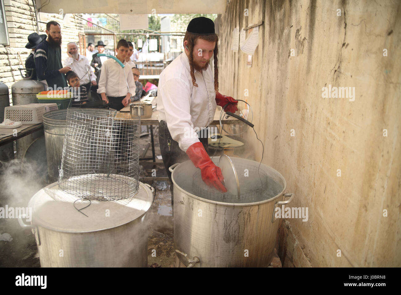 Un homme juif orthodoxe est payé par les clients pour l'immergeant dans l'eau bouillante des plats dans d'énormes pots pour les rendre casher pour les prochaines vacances de Pessah Banque D'Images