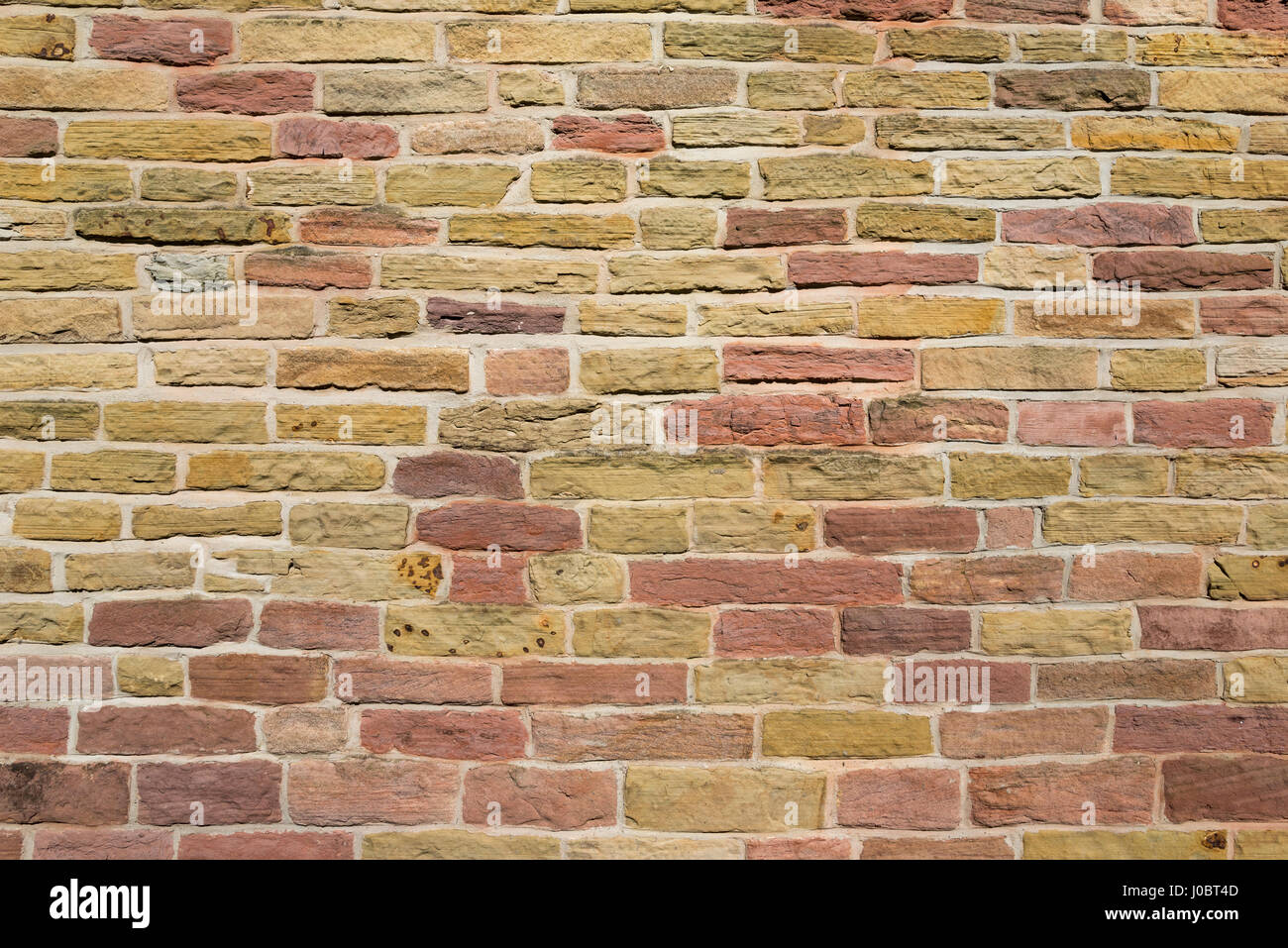 Mur de pierre aux couleurs chaudes. Abstract pattern de vieux sur la maçonnerie d'une petite église à Chadkirk, Stockport, Angleterre. Banque D'Images