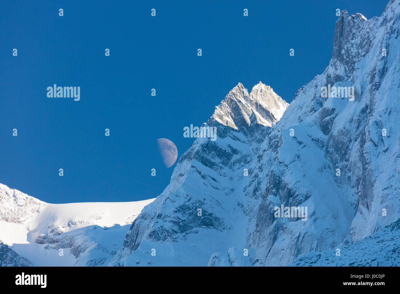 Bleu du ciel et de la lune sur les cimes enneigées du haut des crêtes, des pics Soglio, Vallée Bregaglia, Canton des Grisons, Suisse Banque D'Images