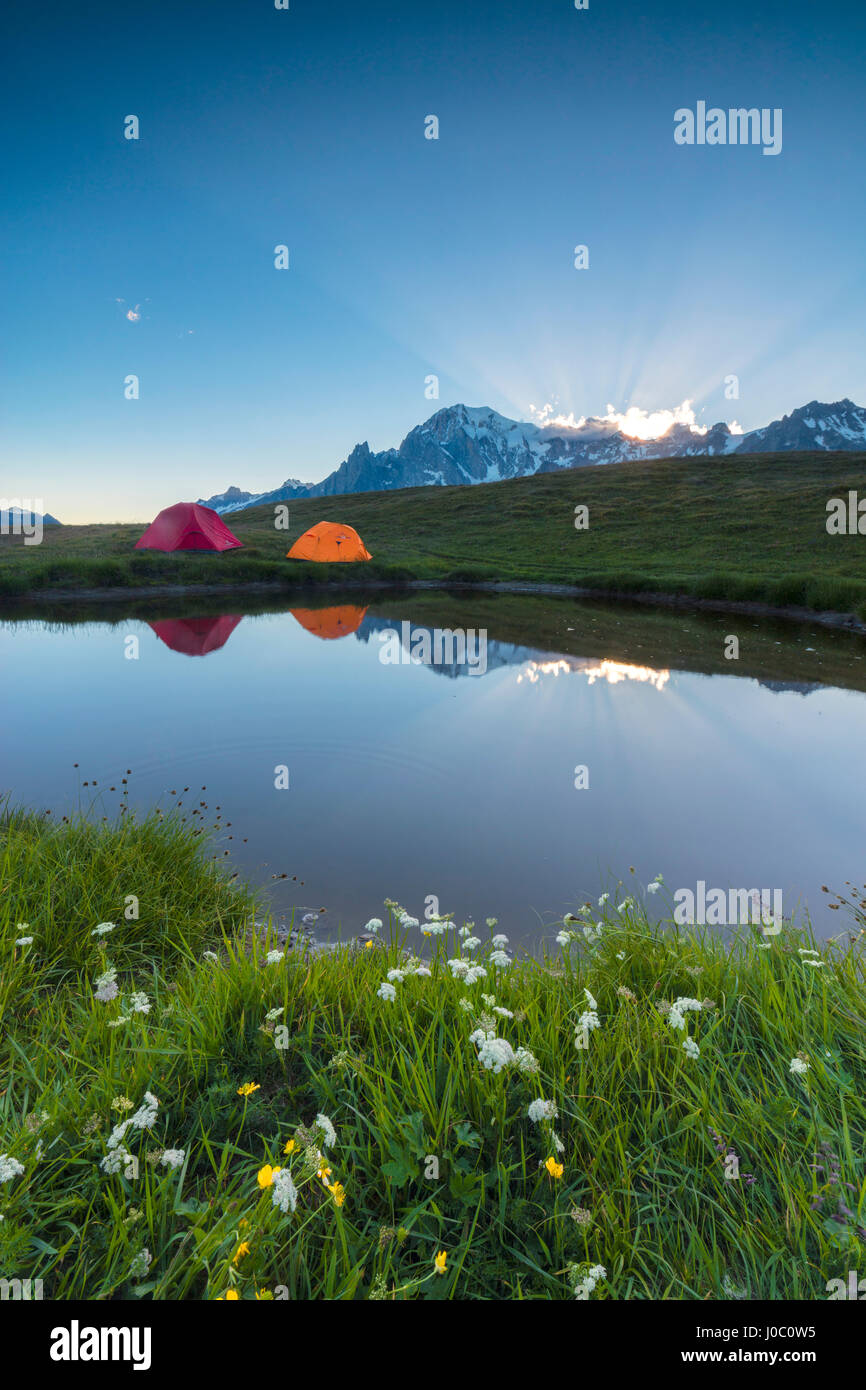 Les tentes de camping dans les verts pâturages entouré de fleurs et de alpine lake, du Mont de la Saxe, Courmayeur, vallée d'aoste, Italie Banque D'Images