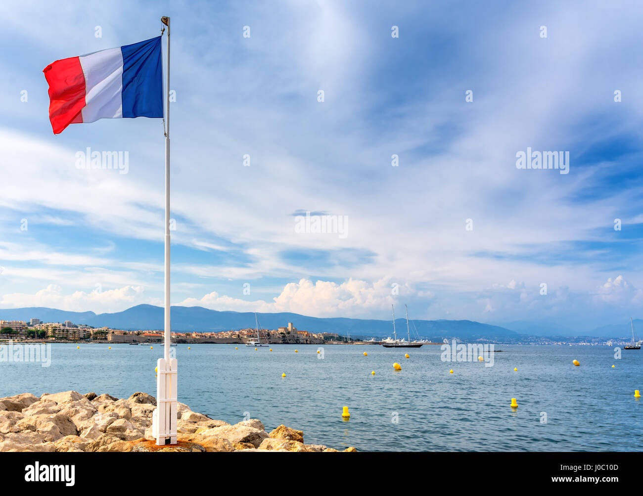 Vue sur la baie avec la France d'un drapeau et d'alpes maritimes à partir de Cap d'Antibes, Antibes. Banque D'Images