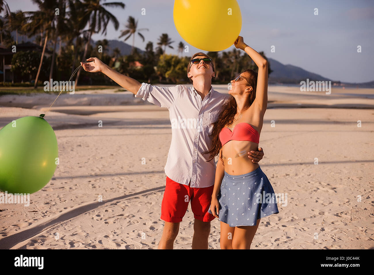 Jeune couple on beach à la recherche jusqu'à des ballons, Koh Samui, Thaïlande Banque D'Images