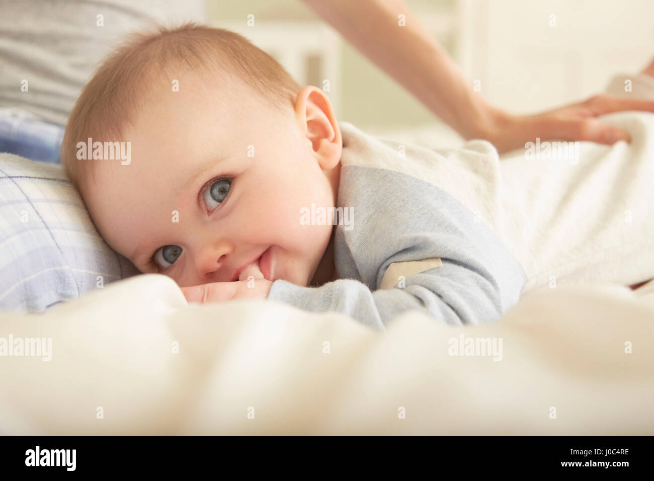 Portrait of baby girl lying on bed with mother Banque D'Images