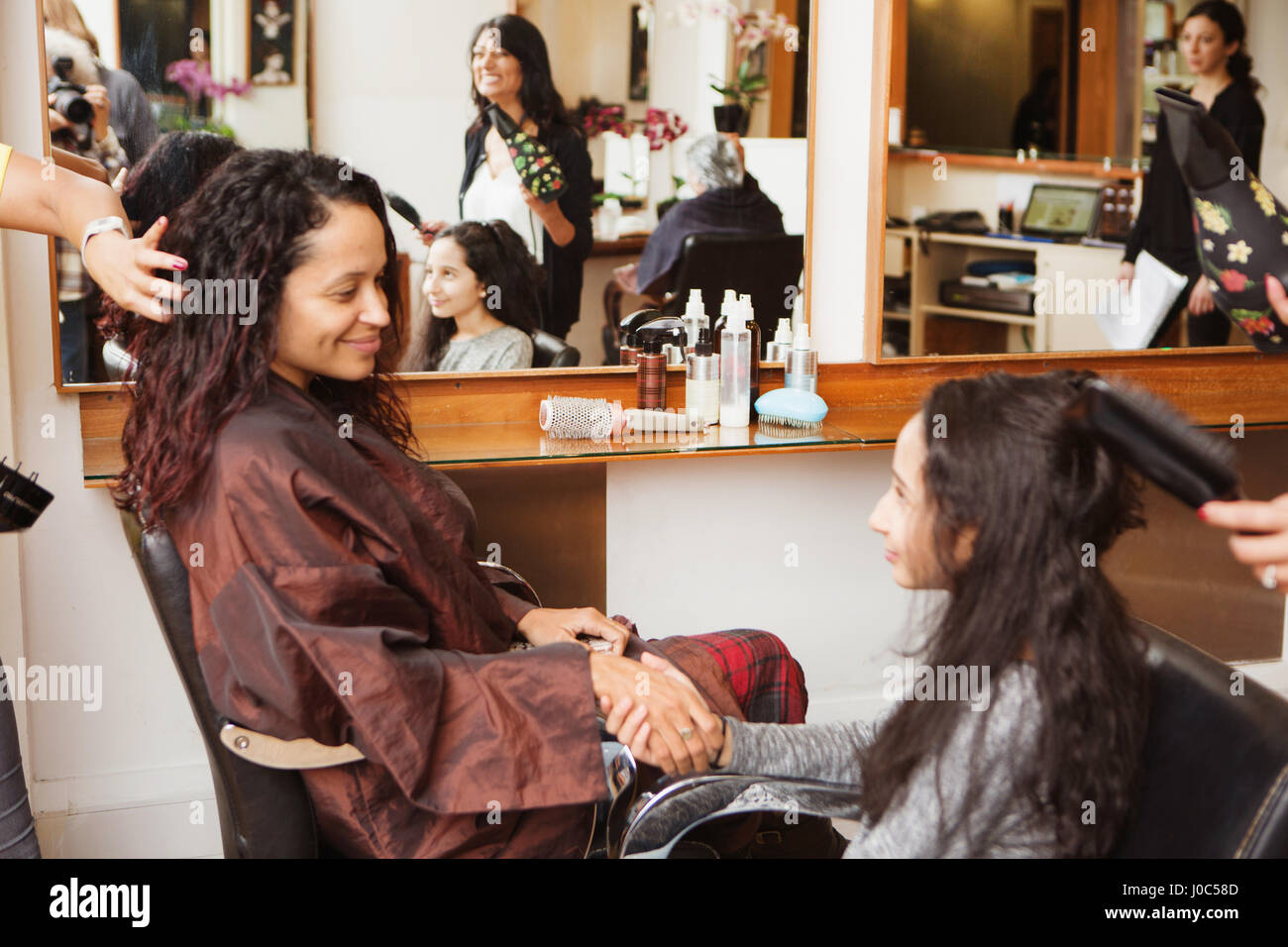 Mère et fille se tenant la main tout en ayant leur style de cheveux dans un salon de coiffure Banque D'Images