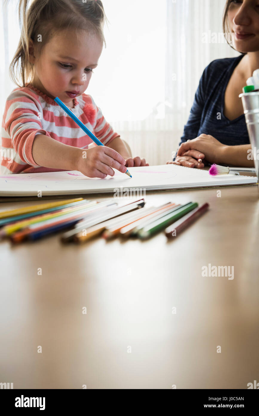 Female toddler à table avec mère dessin dans sketchbook Banque D'Images