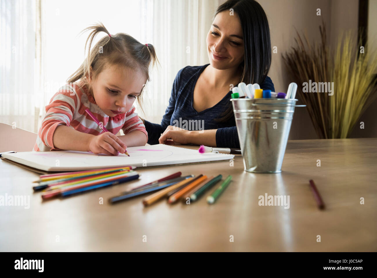 Female toddler à table avec mère dessin dans sketchbook Banque D'Images