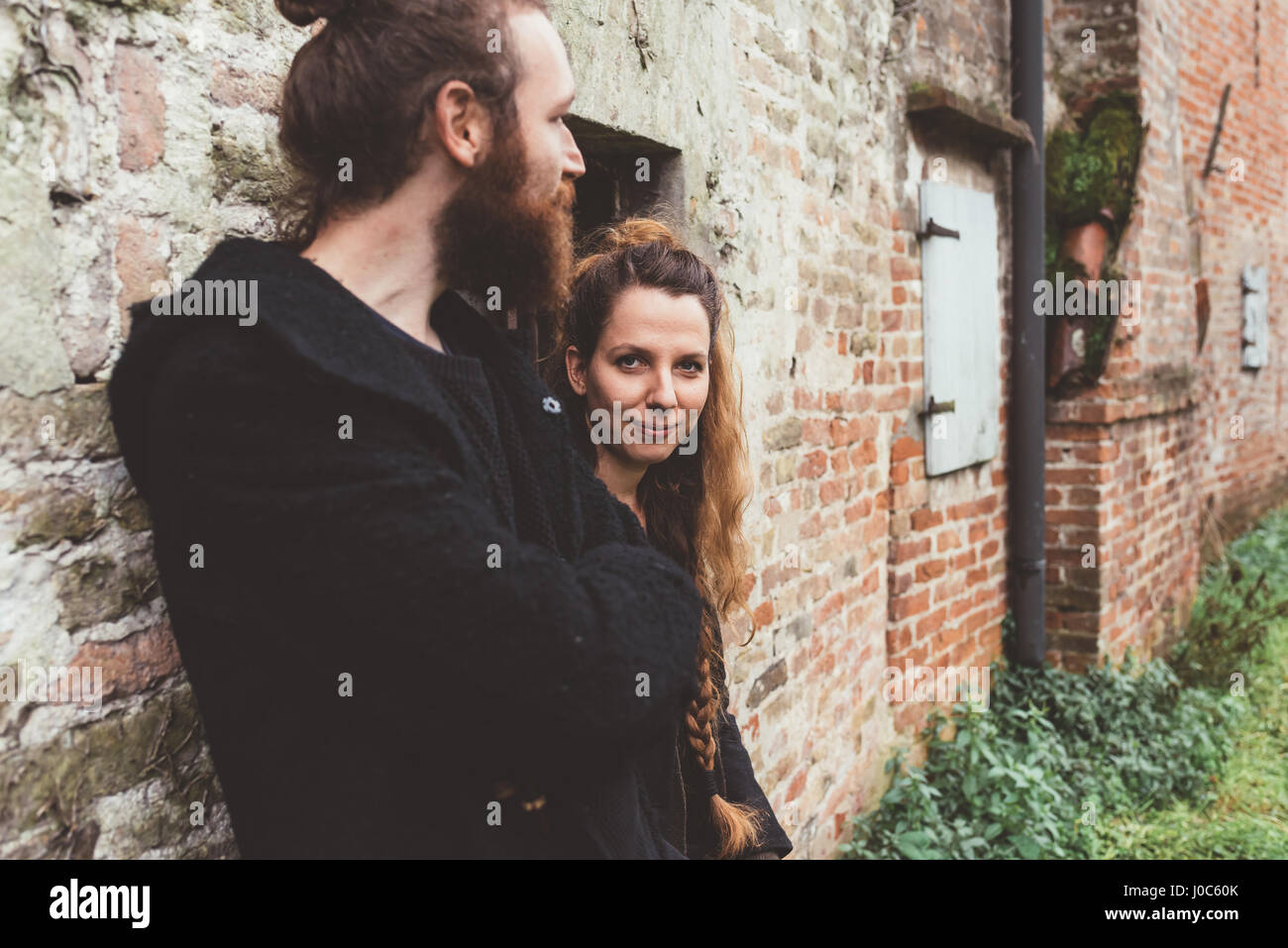 Couple leaning contre l'ancien bâtiment de ferme en brique Banque D'Images