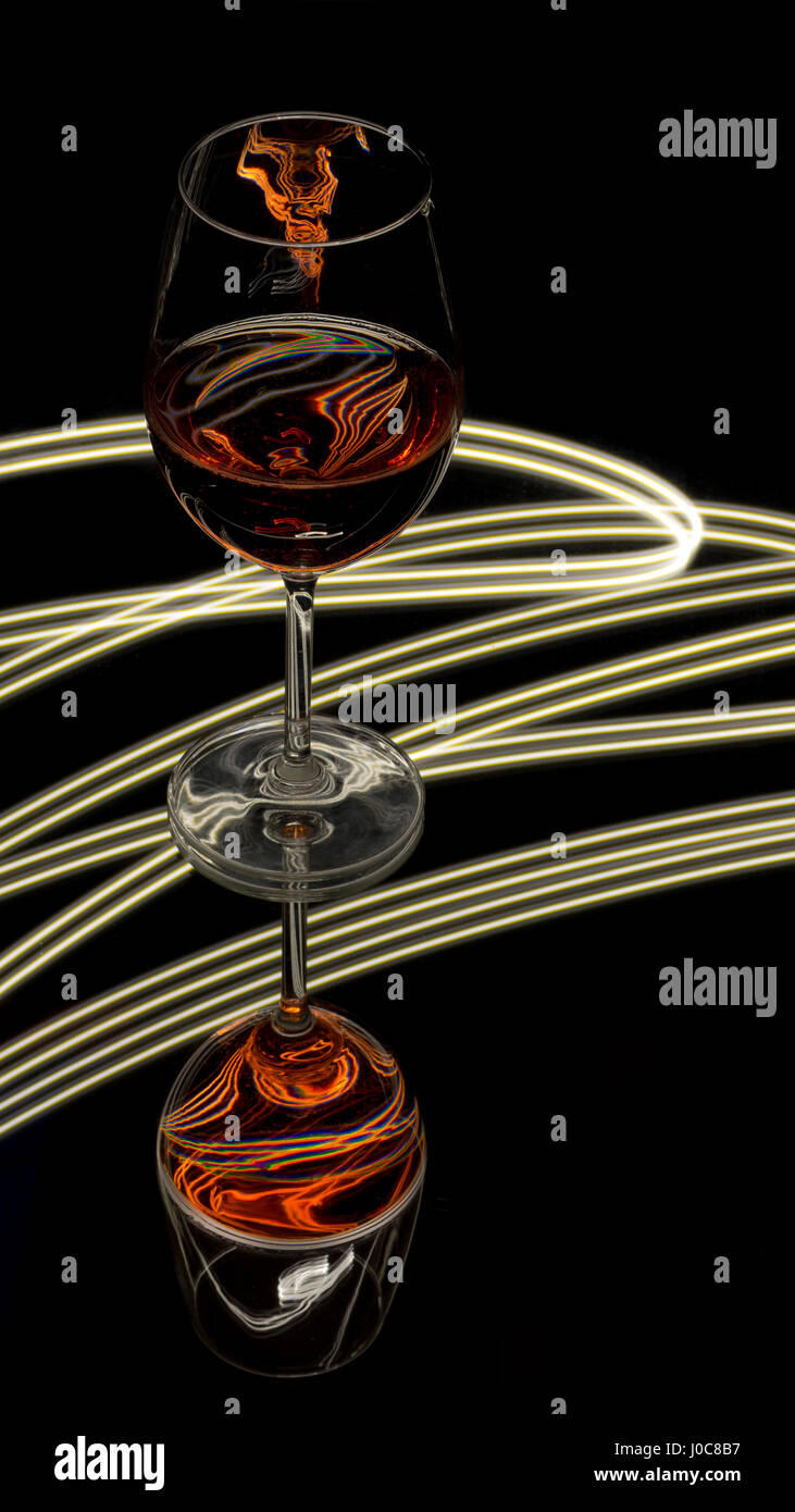 Verre de bon sur un miroir avec les faisceaux lumineux à l'arrière-plan Banque D'Images