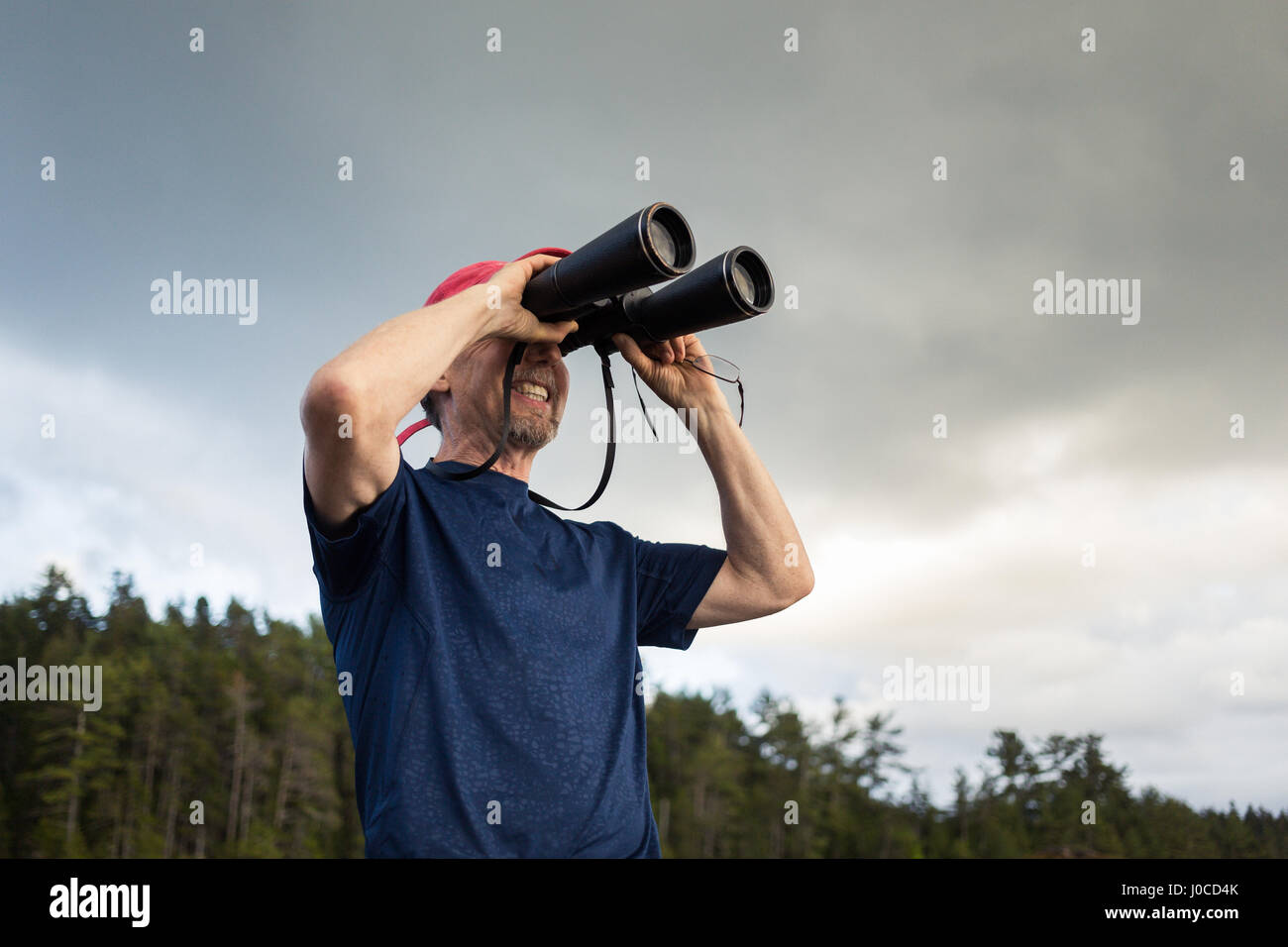 Man looking through binoculars vers côte du Maine, USA Banque D'Images
