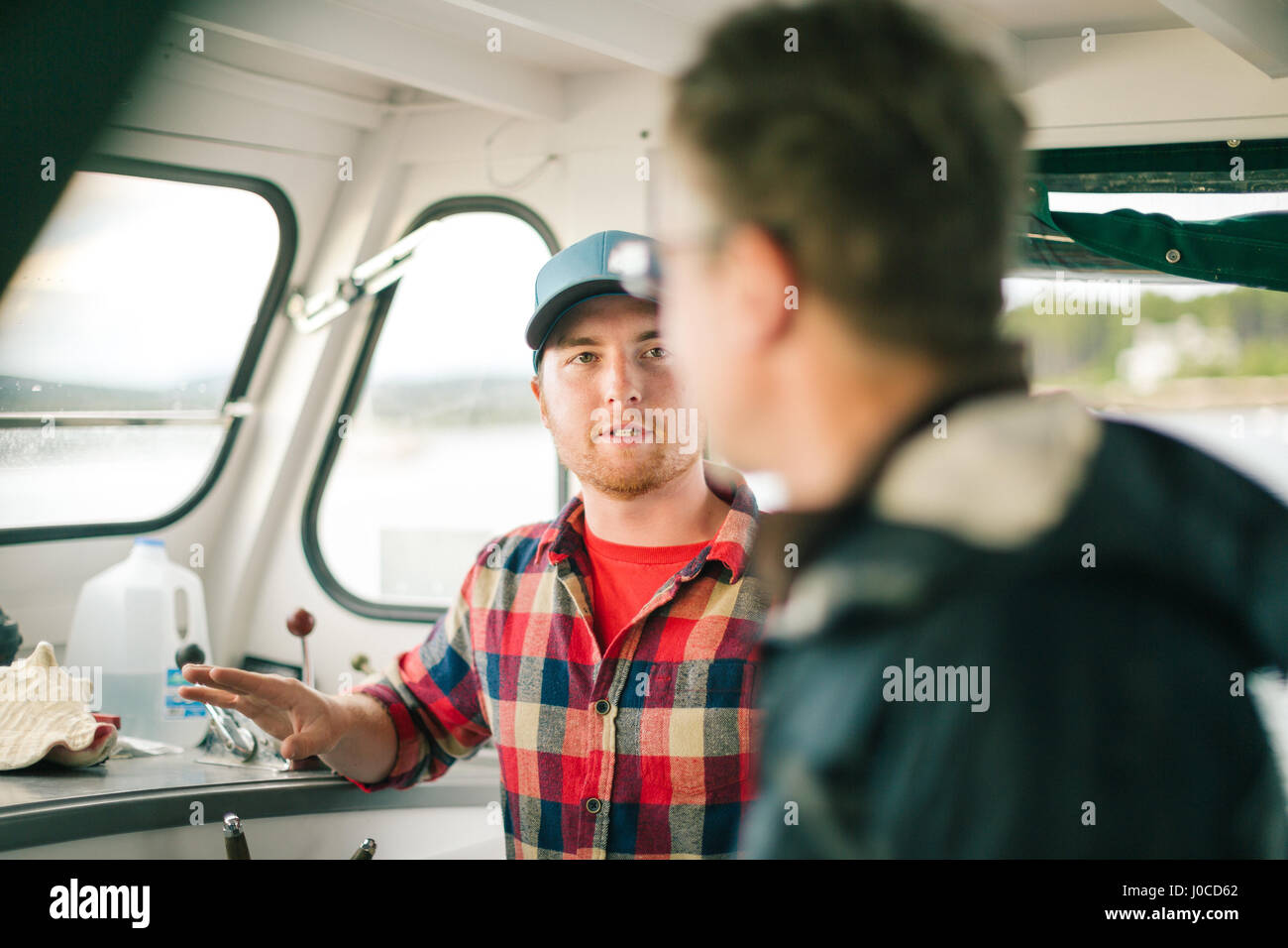 Deux hommes parlant sur bateau de pêche sur la côte du Maine, USA Banque D'Images