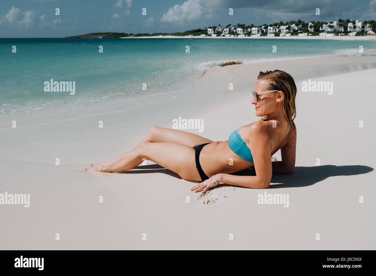 Woman in bikini reclining on beach looking out du blue sea, Anguilla, Saint Martin, Caraïbes Banque D'Images