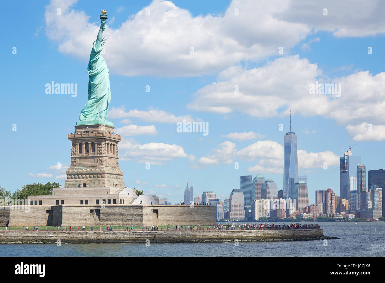 Statue de la liberté et de l'île de New York dans la lumière du soleil, ciel bleu Banque D'Images