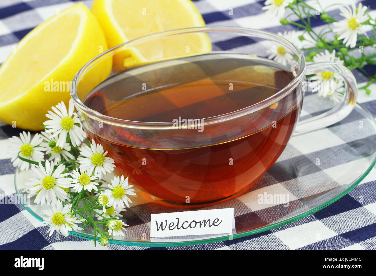 Carte de bienvenue avec une tasse de thé noir, fleurs de camomille et de citron frais Banque D'Images