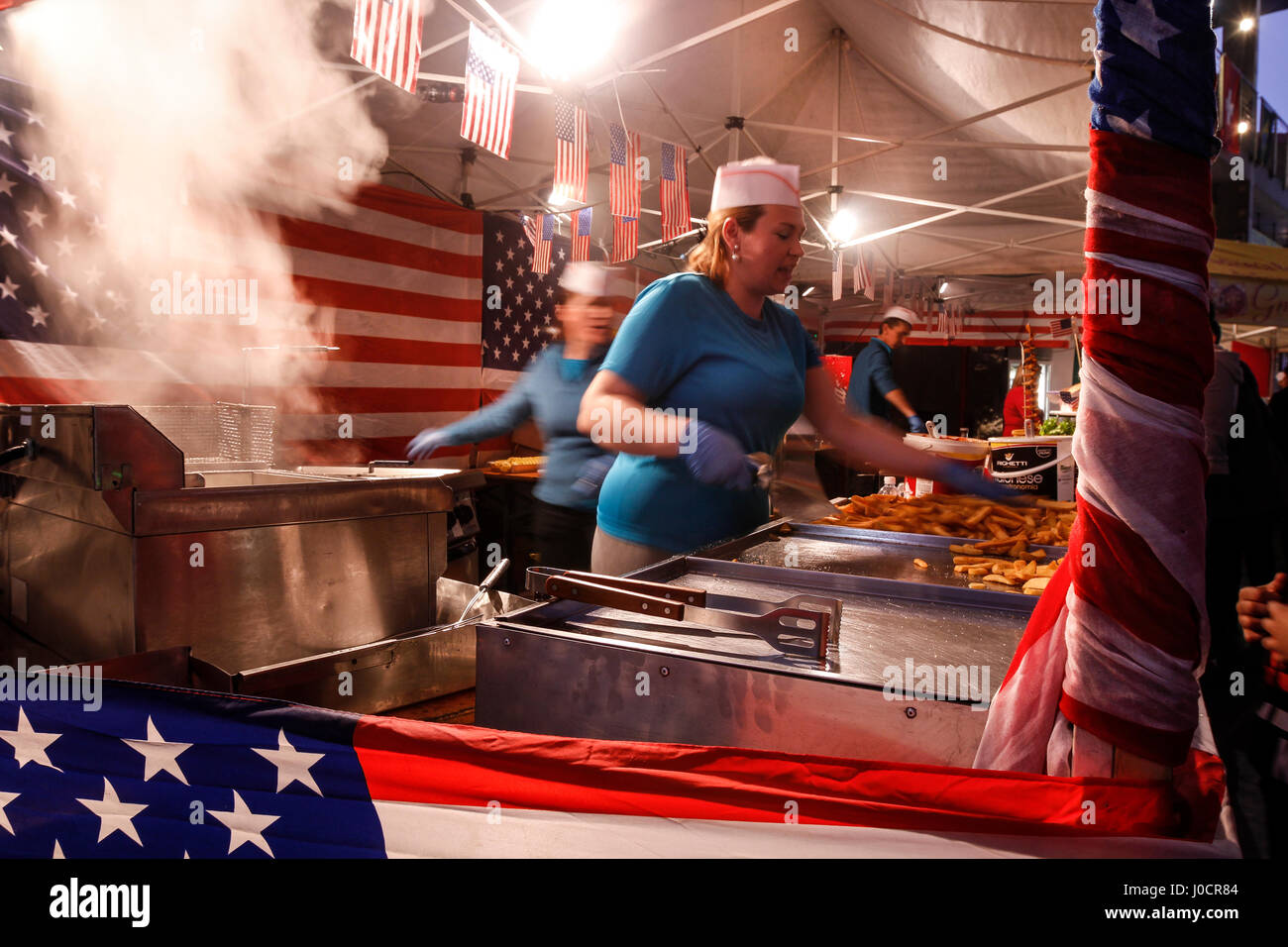 Événement Street food avec des femmes cuisinant des frites dans un stand avec des drapeaux américains. Banque D'Images
