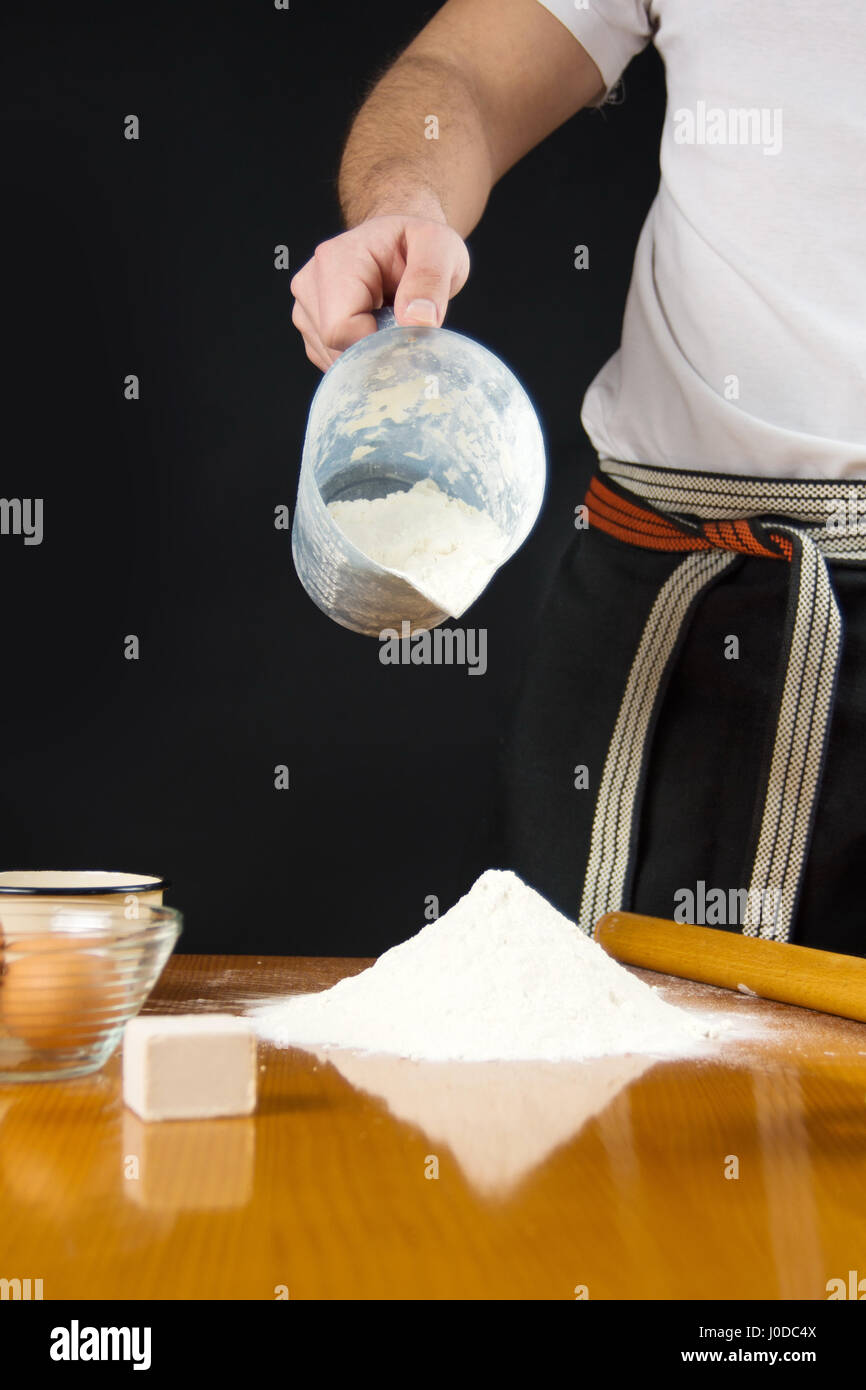 Verser la farine de l'homme mesure bol sur la table Banque D'Images