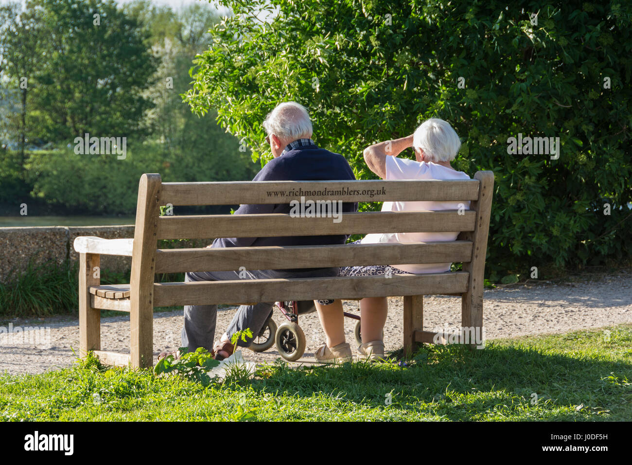 Un couple âgé assis sur un banc de parc à côté du chemin de halage à côté de la Tamise à Londres, Angleterre, Royaume-Uni Banque D'Images