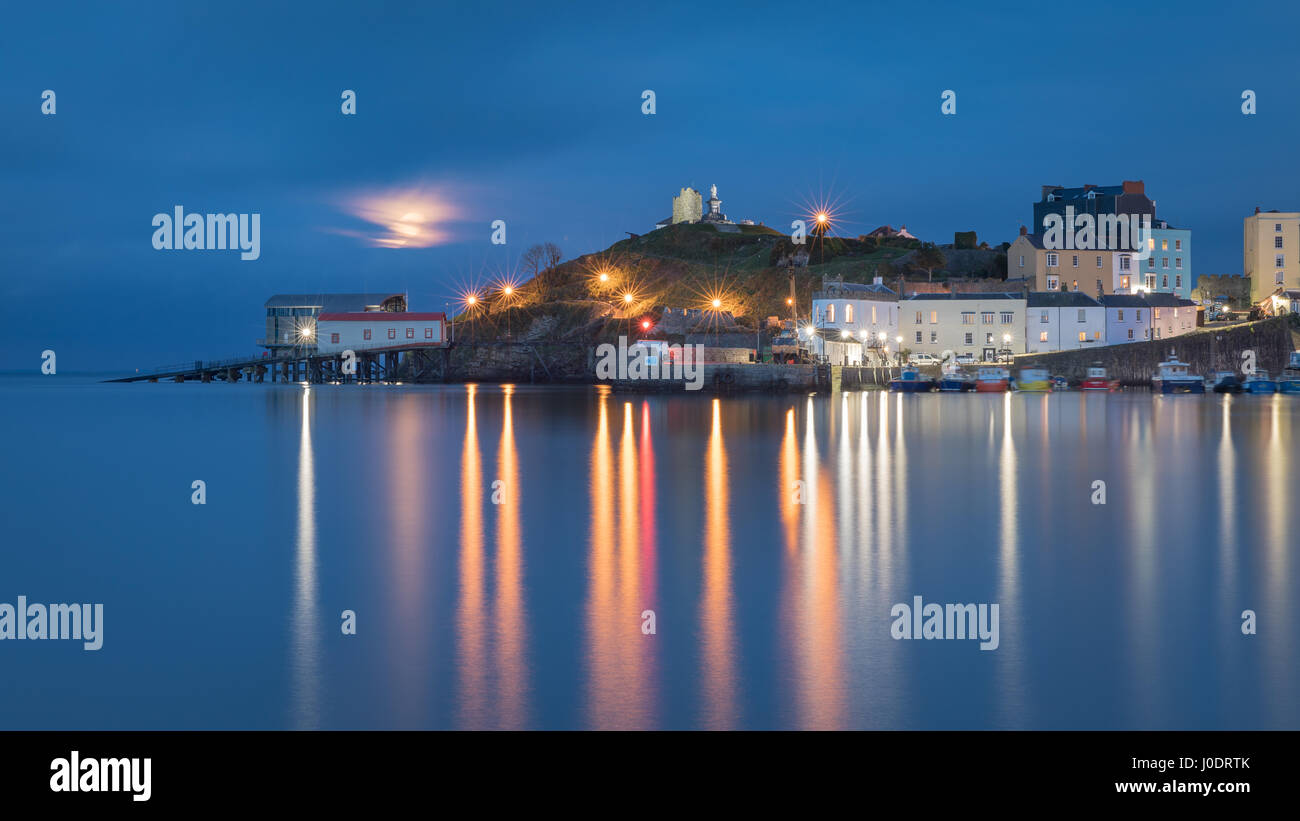 Le 'Pink' Avril pleine lune s'élève au-dessus d'un paisible port de Tenby à marée haute. Dans Pembrokeshire Wales Banque D'Images