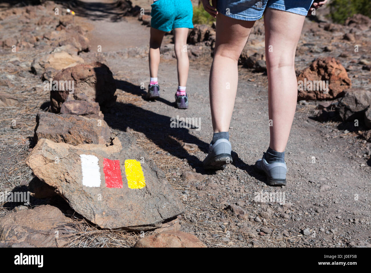 Indiqué avec des couleurs des drapeaux espagnol à vélo à paysage lunaire (Paisaje Lunar). Femme et enfant jambes passant sentier pierreux, Tenerife, Canary Island Banque D'Images