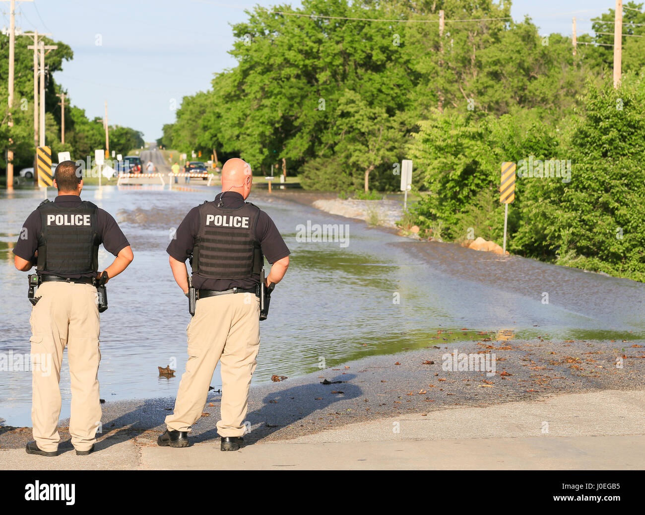 Derby, USA - Le 23 mai 2016 : deux policiers interdire l'une rue inondée, dans le dos des gens avec des voitures devant les obstacles. Banque D'Images