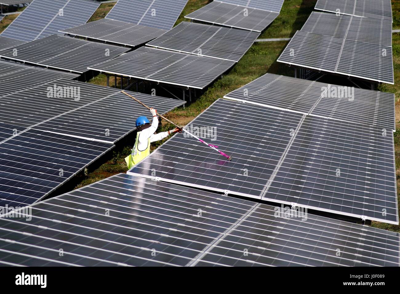 BATANGAS CITY, PHILIPPINES - le 4 février 2017 : un travailleur agricole solaire nettoie un panneau solaire. Banque D'Images